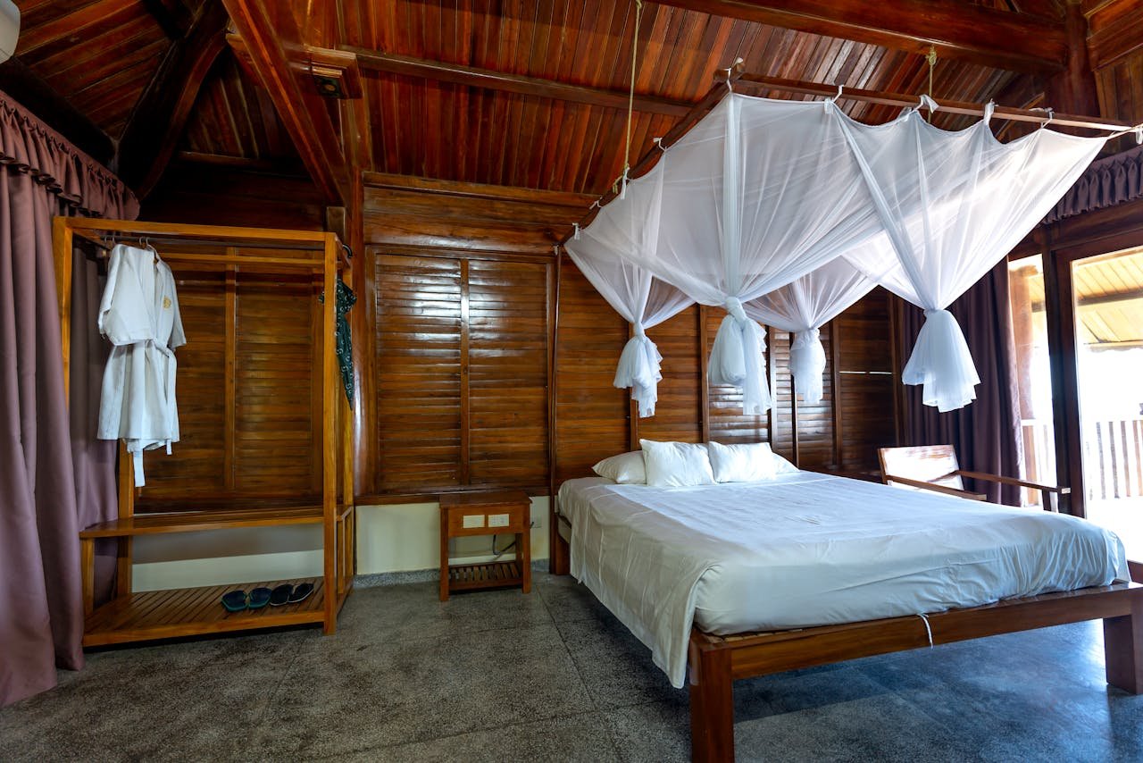 A serene wooden cabin bedroom featuring a canopy bed and rustic interior decor.